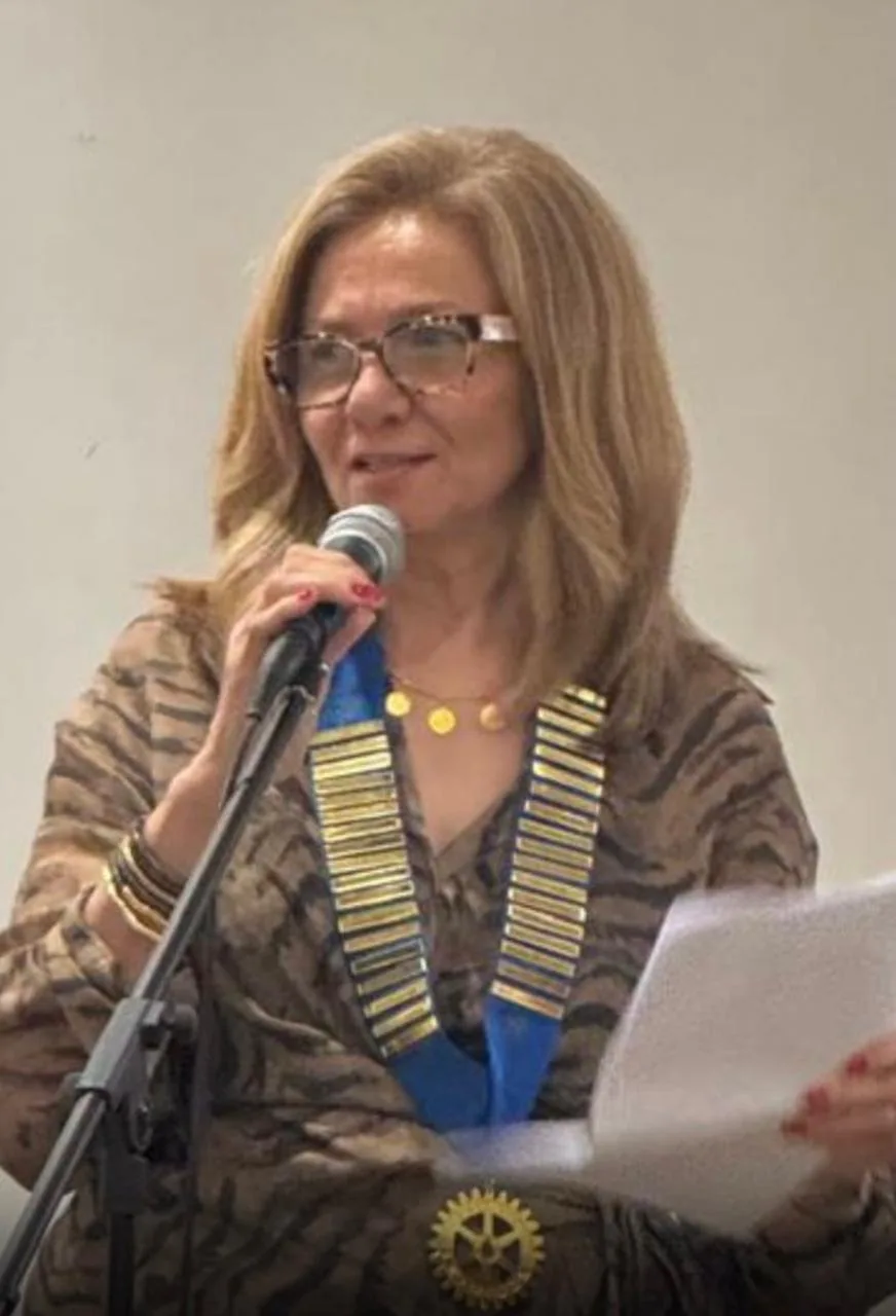 Club President Alia Arafa speaking at a microphone, wearing the president’s collar