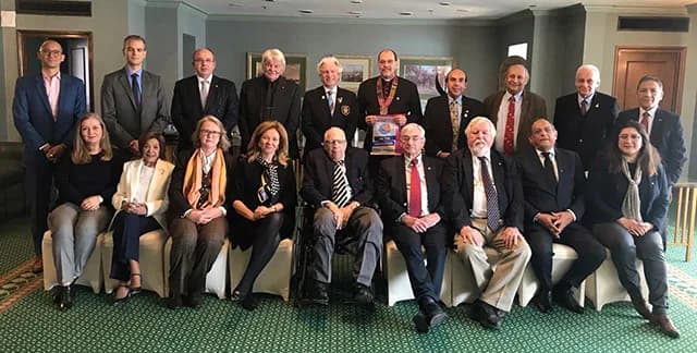 Twenty club members photographed together, the president wearing the chain of office and holding a club plaque